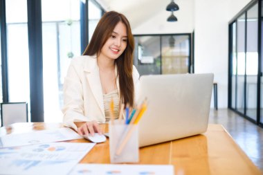 Modern iş istasyonunda çalışan güzel gülümseyen genç girişimci iş kadınının portresi.