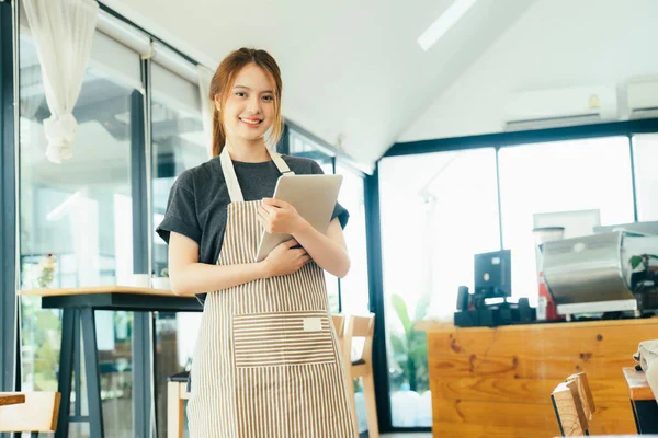 Young business start up owner standing smiling confident and working in coffee shop take an order. Small businessowner concept.