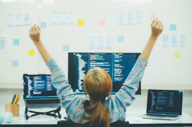 Genç programcı ya da bilişim uzmanı yaptığı işten memnun. Ofisinde çalışırken dizüstü bilgisayarda çalışan mutlu genç bir kadın..