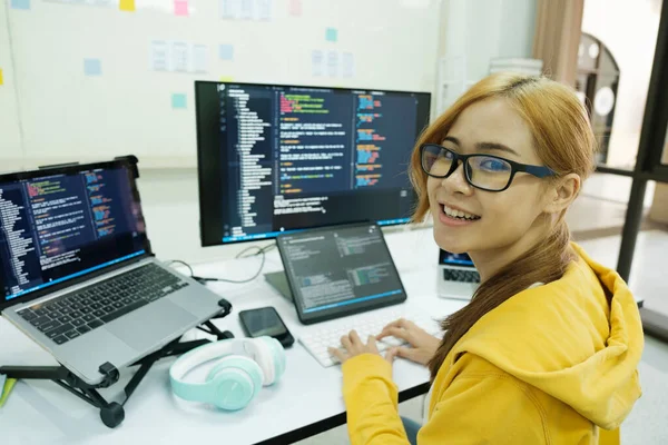 年轻的程序员或It专家对她所做的工作感到满意 坐在办公室工作时 坐在笔记本电脑上工作的年轻快乐女性 — 图库照片
