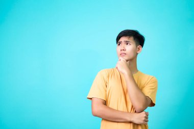 Genç erkekler işaret parmağını kıvrılmış dudakların yanında tutar kaşlarını kaldırmış şüpheli bir şekilde birinin çözüm aradığından şüpheleniyor..