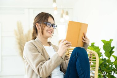Sandalyede oturan genç bir kız öğrenci, online eğitim ya da kendi kendine öğrenim kavramı.