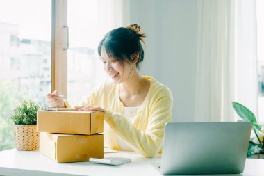 Genç Asyalı iş kadını. İnternet üzerinden müşteri adreslerini posta kutusuna yazıyor..