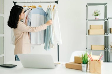 Genç iş adamı, küçük işletmelerdeki kıyafetleri kontrol ediyor. Depodaki envanteri kontrol ediyor. Mağaza teftişi.