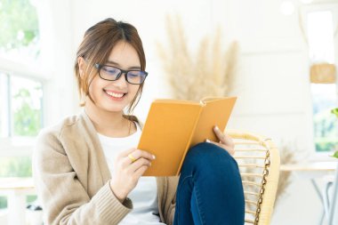 Sandalyede oturan genç bir kız öğrenci, online eğitim ya da kendi kendine öğrenim kavramı.