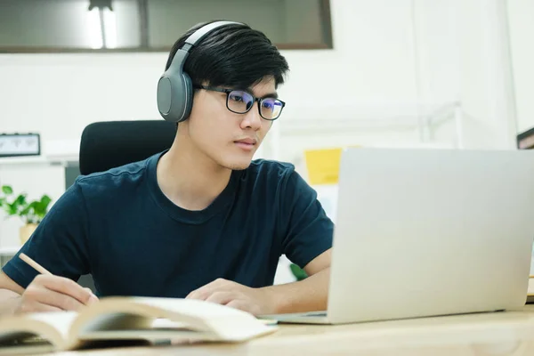 若い男性学生は家で勉強する ノートパソコンを使ってオンラインで学ぶ — ストック写真