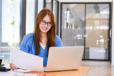 Bir kız üniversite öğrencisi internete çevrimiçi öğrenme ve çevrimiçi iş yapmak için bir bilgisayar kullanır. Çevrimiçi öğrenim kavramı.