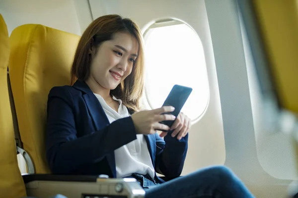 Young businesswoman In a plane using using on phone computer during In a plane flight, travel concept.