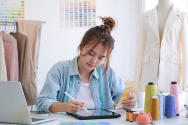 Moda tasarımcısı stüdyoda çalışıyor, çizim kesme, dikiş elbise