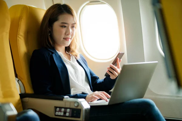 Young businesswoman In a plane using on laptop computer during In a plane flight, travel concept.