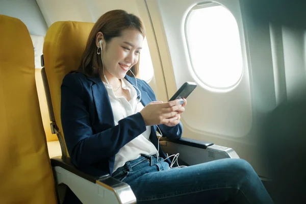 Young businesswoman In a plane using using on phone during In a plane flight, travel concept.