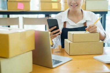 Start up small business owner writing address on cardboard box a and Always keep contact with customer.