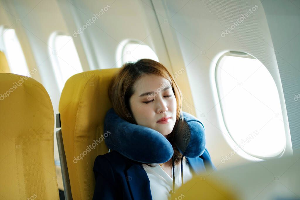 Young businesswoman In a plane sleeping on the plane on the go, travel concept.