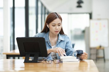 Genç bayan öğrenci evde ders çalışıyor. Bilgisayarı kullanması ve internetten öğrenmesi..