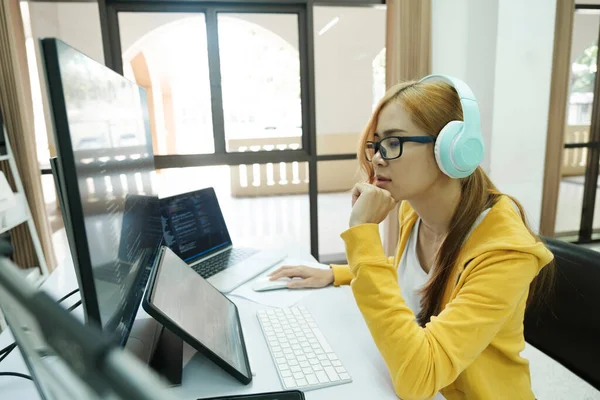 Young woman programmer sitting at table in front of laptop, sleepy, tired, overworked, lazy to work. Business woman yawning in home office relaxing or bored after work on laptop computer.