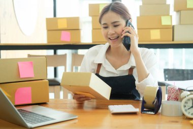 Genç Asyalı iş kadını girişimci KOBİ sahibi müşteriyle birlikte bir iç kutuya koymadan önce sarı bir gömlek aldı. Çevrimiçi İş Fikirleri ve Serbest Çalışmalar.