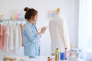 Moda tasarımcısı stüdyoda çalışıyor, çizim kesme, dikiş elbise