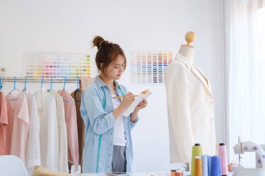 Moda tasarımcısı stüdyoda çalışıyor, çizim kesme, dikiş elbise