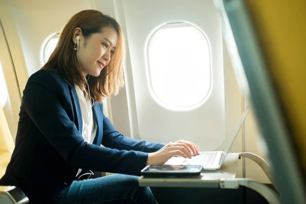 Young businesswoman In a plane using on laptop computer during In a plane flight, travel concept.