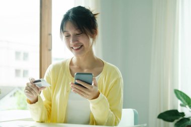 Akıllı telefondan alışveriş yapmak için kredi kartı kullanan Asyalı kadını kapat..