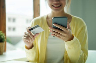 Akıllı telefondan alışveriş yapmak için kredi kartı kullanan Asyalı kadını kapat..