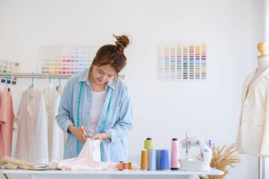 Moda tasarımcısı stüdyoda çalışıyor, çizim kesme, dikiş elbise