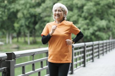 Athletic Senior woman running in the morning outdoor jogging in park.