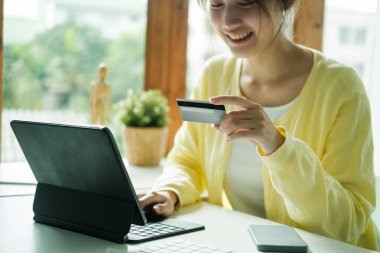 Close up asian woman using credit card for purchasing and shopping online on laptop computer.