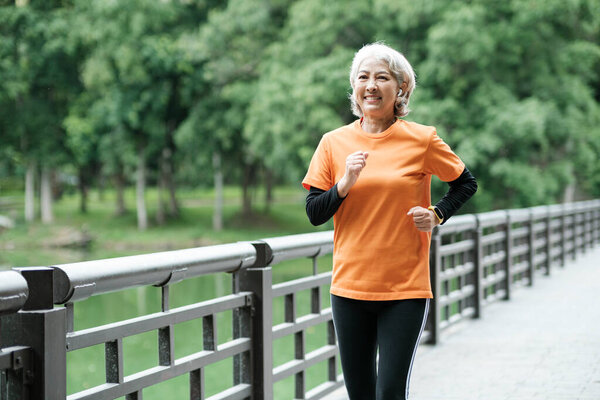 Athletic Senior woman running in the morning outdoor jogging in park.