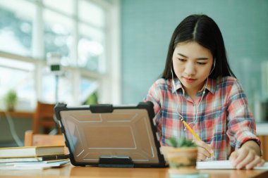 Young asian woman student study at offsite. Her using laptop and learning online and using headphones.