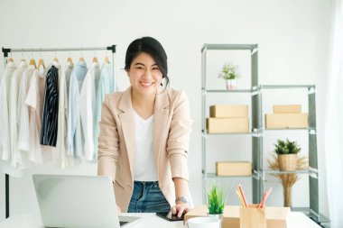 Happy young asian female freelan standing in online clothing store.Work at home concept. work from home.