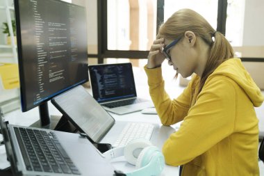 Young woman covering her face with the stress of work coding and programming software. frustrated on her work and out of control..