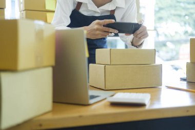 Asian business owner Smiling young women taking smartphone picture the product been packed for the buyer. The concept of online sales of plant.