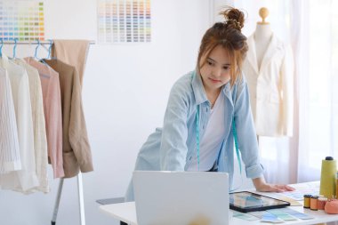 Moda tasarımcısı stüdyoda çalışıyor, çizim kesme, dikiş elbise