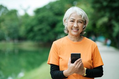 Happy athletic Senior woman in park before running in park, health concept.