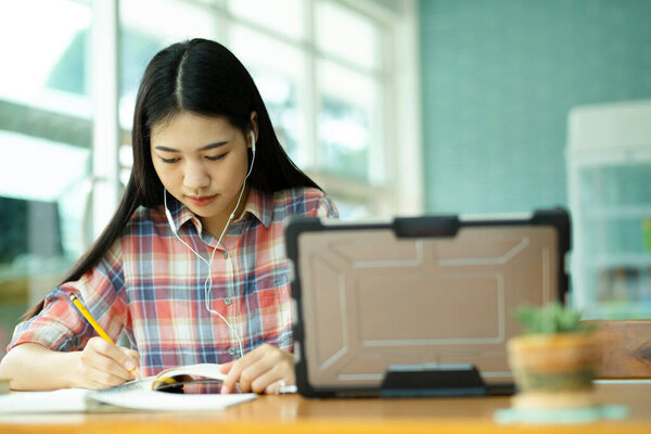 Young asian woman student study at offsite. Her using laptop and learning online and using headphones.