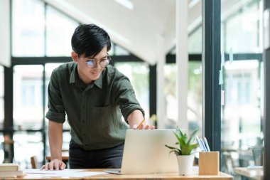 Young Asian man excited by good news celebrate success or happy pose with laptop.