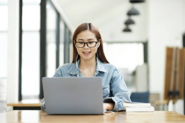 Genç bayan öğrenci evde ders çalışıyor. Bilgisayarı kullanması ve internetten öğrenmesi..