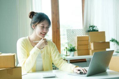 Young asian business owner working with calculator, The seller prepares the delivery box for the customer with postal parcel. Selling online and delivery.