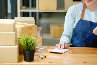 Close up with mall business owner working with calculator, The seller prepares the delivery box for the customer with postal parcel. Selling online and delivery.