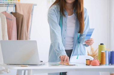 Moda tasarımcısı stüdyoda çalışıyor, çizim kesme, dikiş elbise
