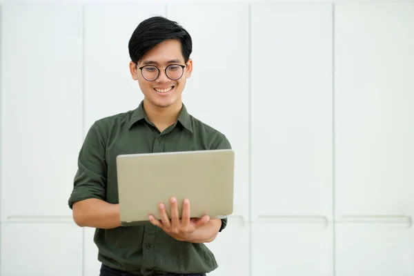 Smiling asian business man online working on laptop at home office. Young boy asian student or remote teacher using computer online studying, virtual training, watching online education webinar at