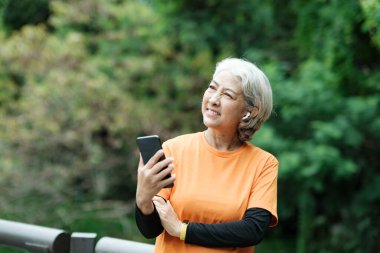 Happy athletic Senior woman checking her smartwatch in the park, Concept of a healthy lifestyle on retirement. health concept.