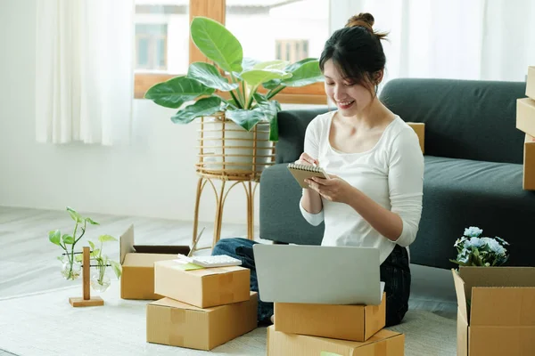 Young asian business owner working with calculator, The seller prepares the delivery box for the customer with postal parcel. Selling online and delivery.