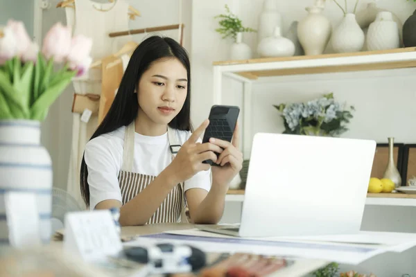 Young asian businesswoman sitting in house inspection product and to contact customers on smatphone. Store house inspection.