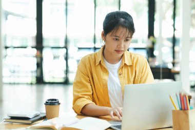 Evde çalışan genç bir kız öğrenci. Bilgisayarı kullanıyor ve internetten öğreniyor..