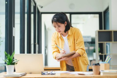 Gülümseyen Asyalı iş kadını ev bilgisayarında çalışıyor. Genç Asyalı öğrenci ya da uzaktan öğretmen bilgisayar kullanıyor. İnternette öğrenim görüyor, sanal eğitim veriyor, internet üzerinden eğitim alıyor..