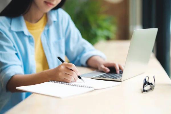 テーブルに座っている間 ラップトップを使用して勉強し 書く女性のクローズアップ ノートパソコンをテーブルに座ってオンラインで勉強し 学習しながら 学生の書き込みやメモを取る オンライン学習の概念 — ストック写真