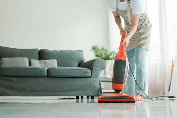Young woman in casual clothes cleaning floor using vacuum cleaner and cleaning equipments in living room at home. Housekeeping concept.
