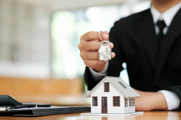住宅モデルとキーを保持する不動産代理店 コンサルティング および顧客と相談して住宅を購入するための保険フォーム契約を締結することを決定する 不動産の概念 — ストック写真